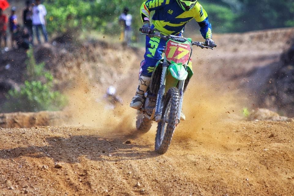 A motocross rider charging through a spray of dirt