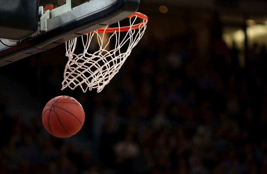 A basketball dropping through the net in a dark arena