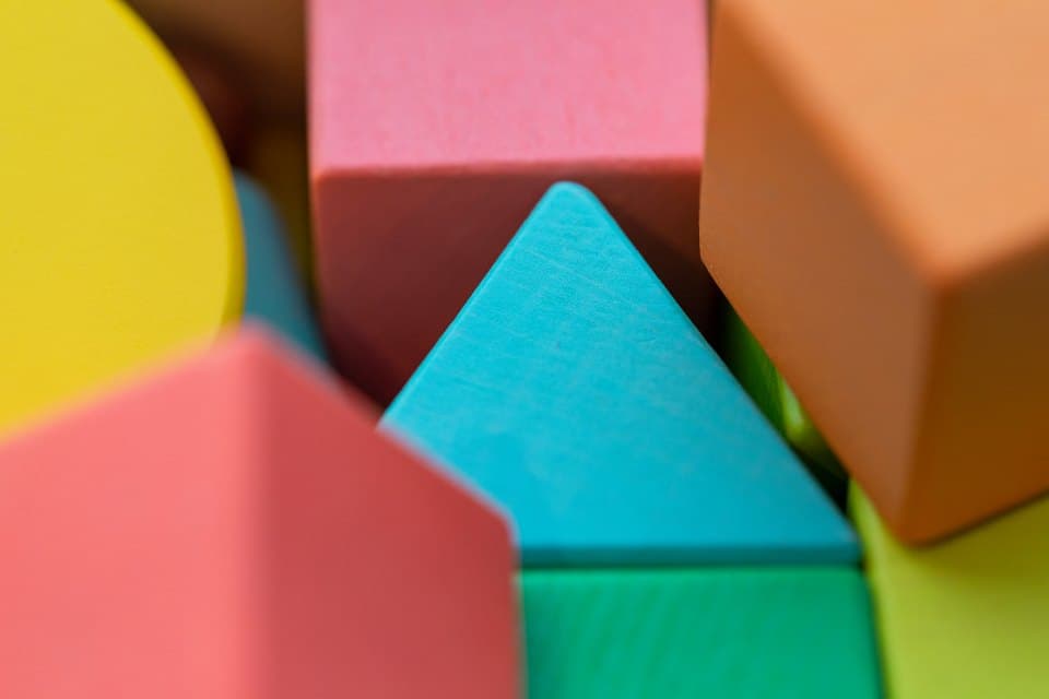 Bright wooden toy blocks in pink, yellow and teal